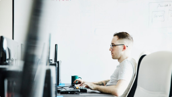 Personne assise à un bureau travaillant sur son ordinateur 
