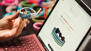 Woman holding a bracelet working on a Surface Pro.