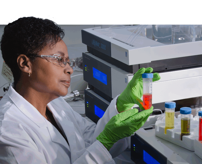 Woman holding vial of red liquid with other vials of colored liquid on the table in front of her